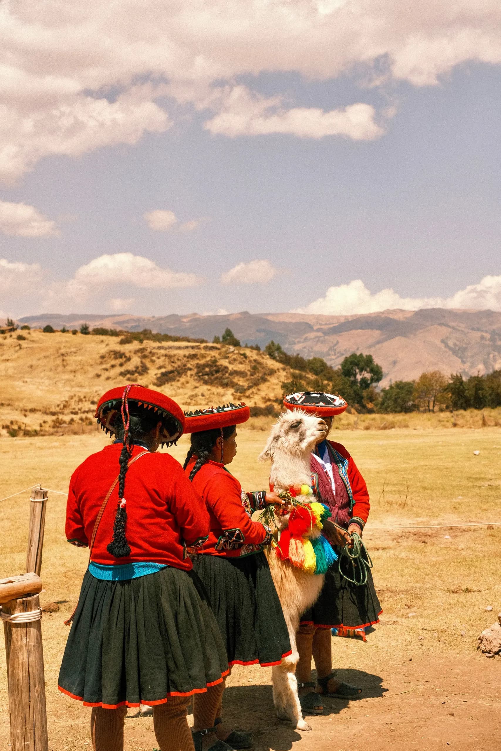 © Adrien Daurenjou · Pexels Women in Andean clothing with a llama beside a rural path