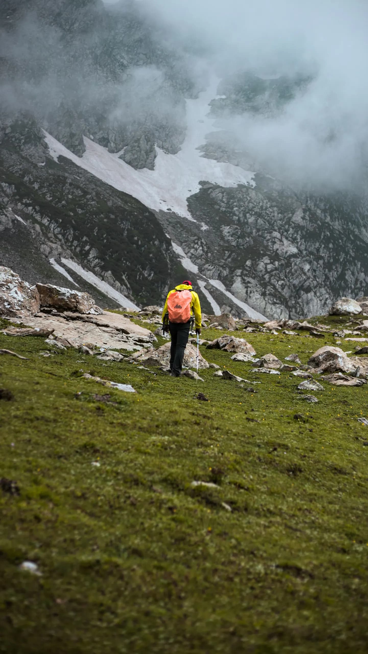 © Sheikh Abrar Ul Haq · Pexels Hiker following a trail between rocky slopes and cloud-covered mountains