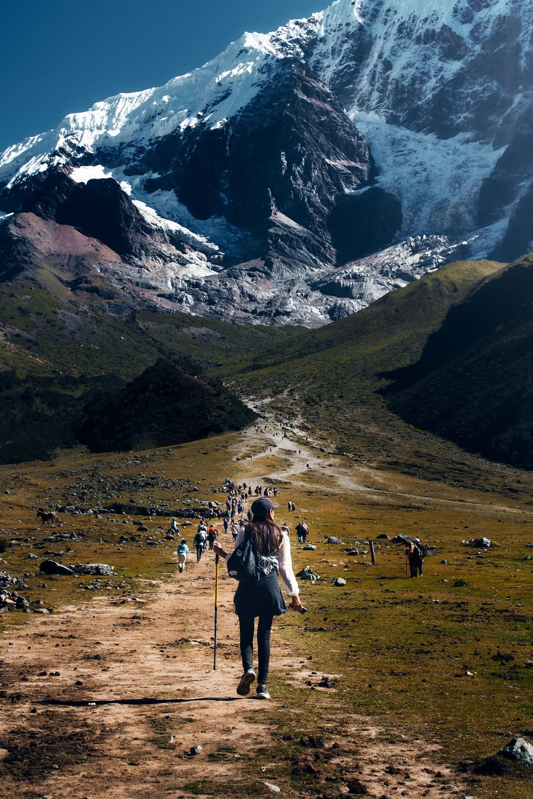 © gala briela · Pexels Hiker on a trail below a snowy peak